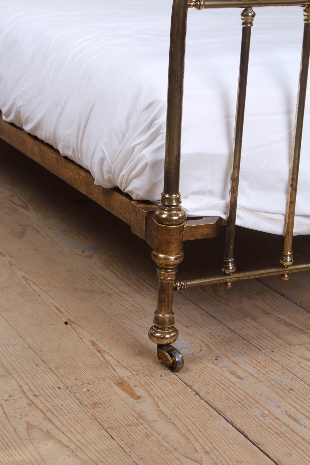 An antique French brass single bed frame featuring an arched headboard and footboard decorated with circular hoop motifs and vertical spindles. View II