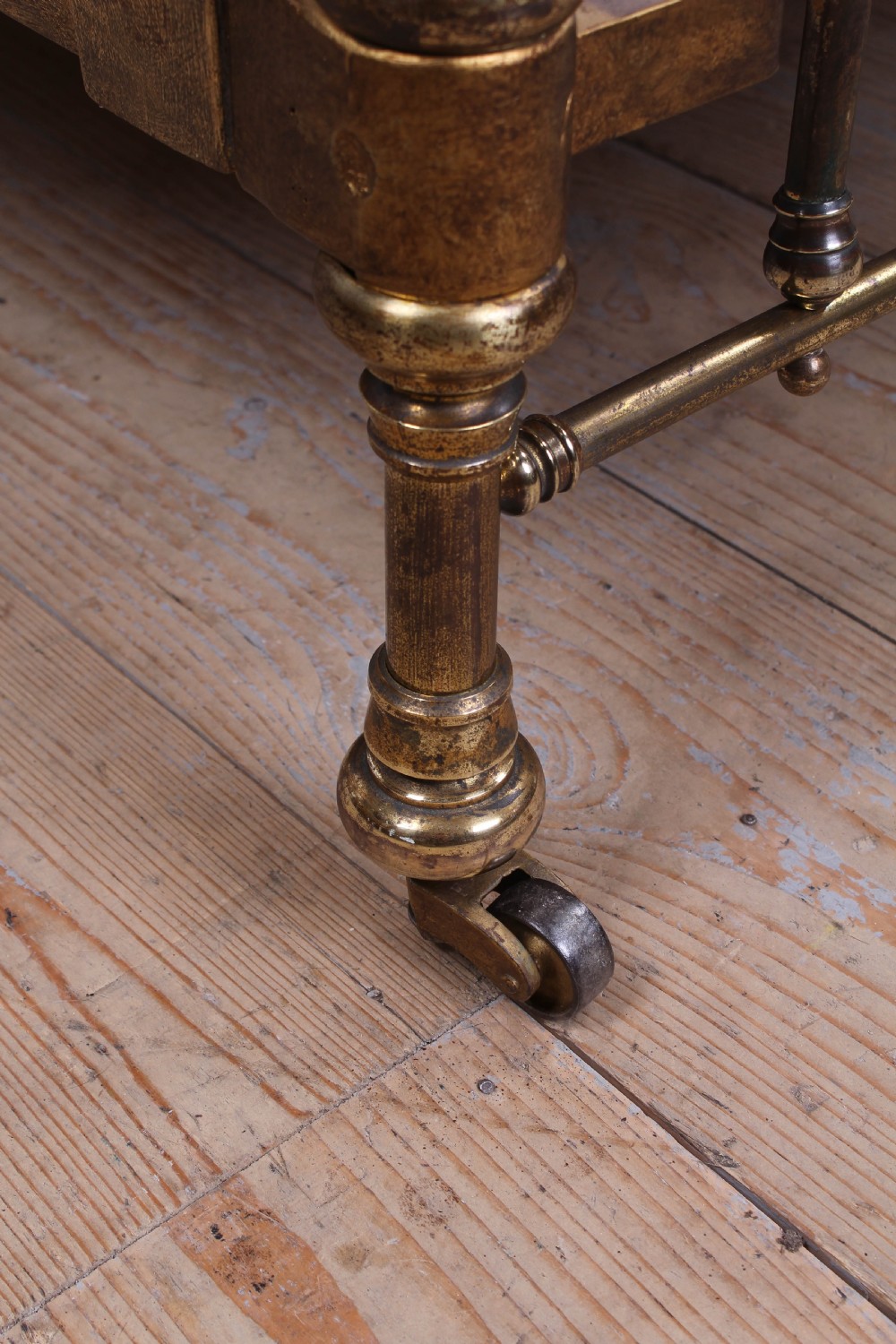 An antique French brass single bed frame featuring an arched headboard and footboard decorated with circular hoop motifs and vertical spindles. View V