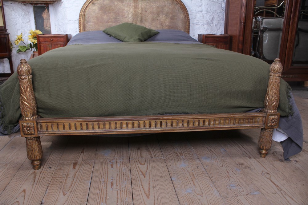 A French Neoclassical king-size bed featuring a carved giltwood frame with an arched caned headboard and detailed fluted posts. View VI