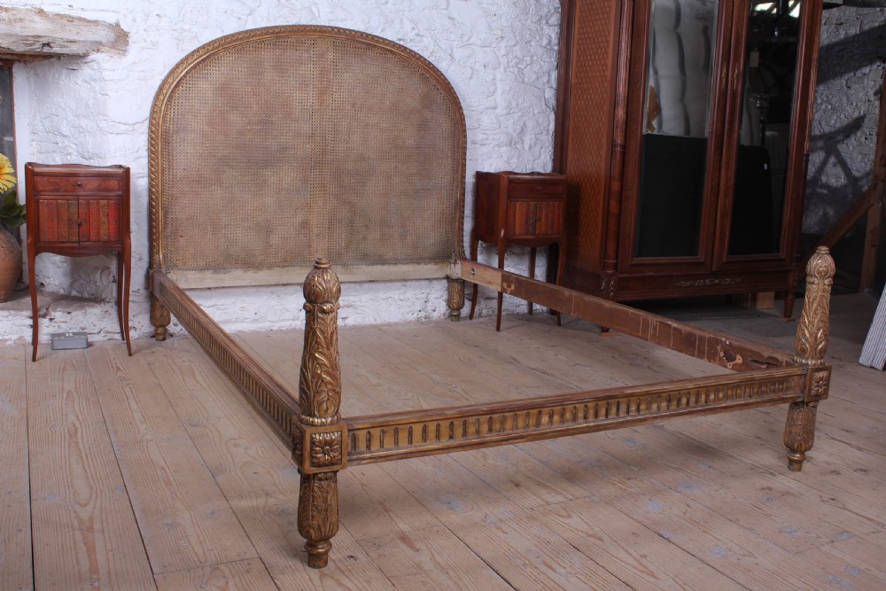 A French Neoclassical king-size bed featuring a carved giltwood frame with an arched caned headboard and detailed fluted posts. View VIII