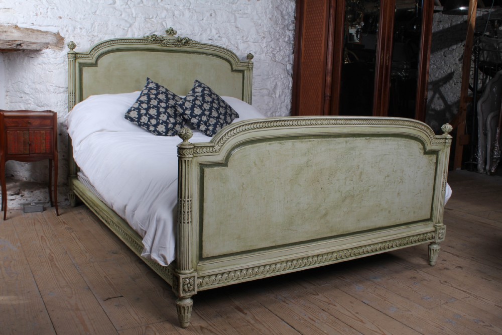 A French Louis XVI style king size bedstead in distressed sage green paint with carved fluted posts and decorative molding. View III