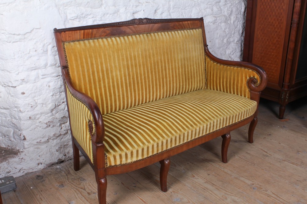 A French Directoire two-seater sofa featuring a polished fruitwood frame and yellow striped velvet upholstery secured with brass studding. View V