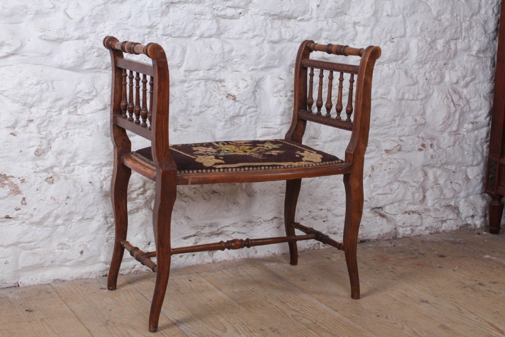 A French wooden stool featuring raised spindled side galleries, turned stretchers, and a dark floral tapestry seat fastened with brass studs. View II