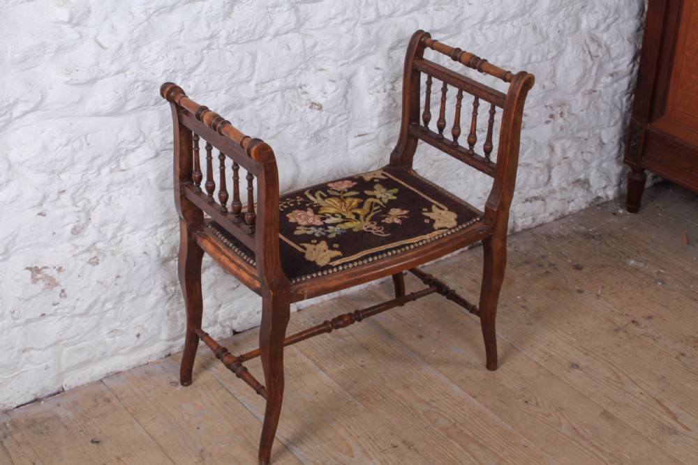 A French wooden stool featuring raised spindled side galleries, turned stretchers, and a dark floral tapestry seat fastened with brass studs. View IV