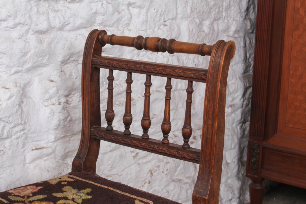 A French wooden stool featuring raised spindled side galleries, turned stretchers, and a dark floral tapestry seat fastened with brass studs. View V