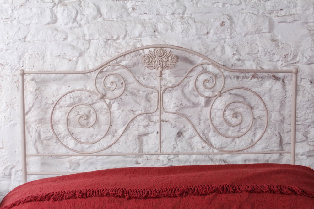 An off-white painted forged iron double bed frame featuring an arched headboard decorated with scrollwork and a low-profile foot end. View II