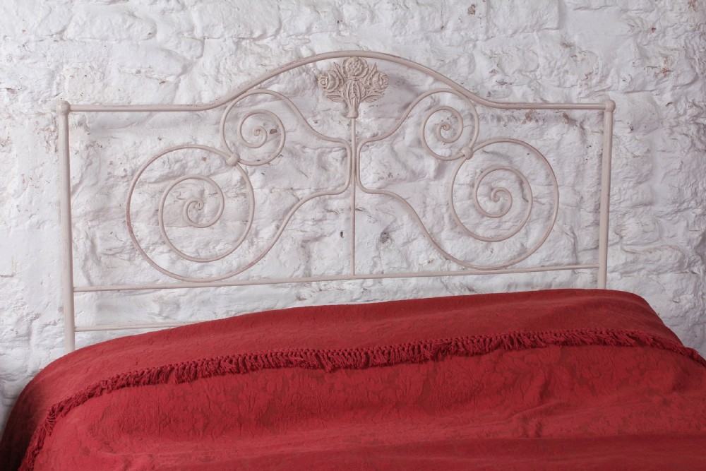 An off-white painted forged iron double bed frame featuring an arched headboard decorated with scrollwork and a low-profile foot end. View III