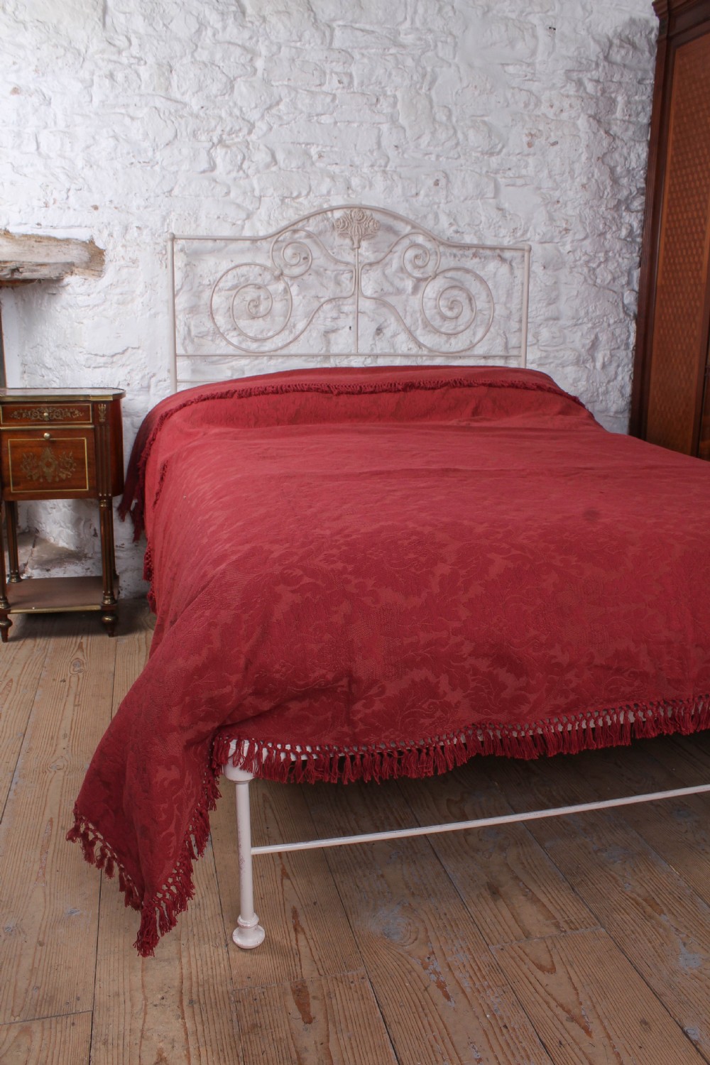 An off-white painted forged iron double bed frame featuring an arched headboard decorated with scrollwork and a low-profile foot end. View IV