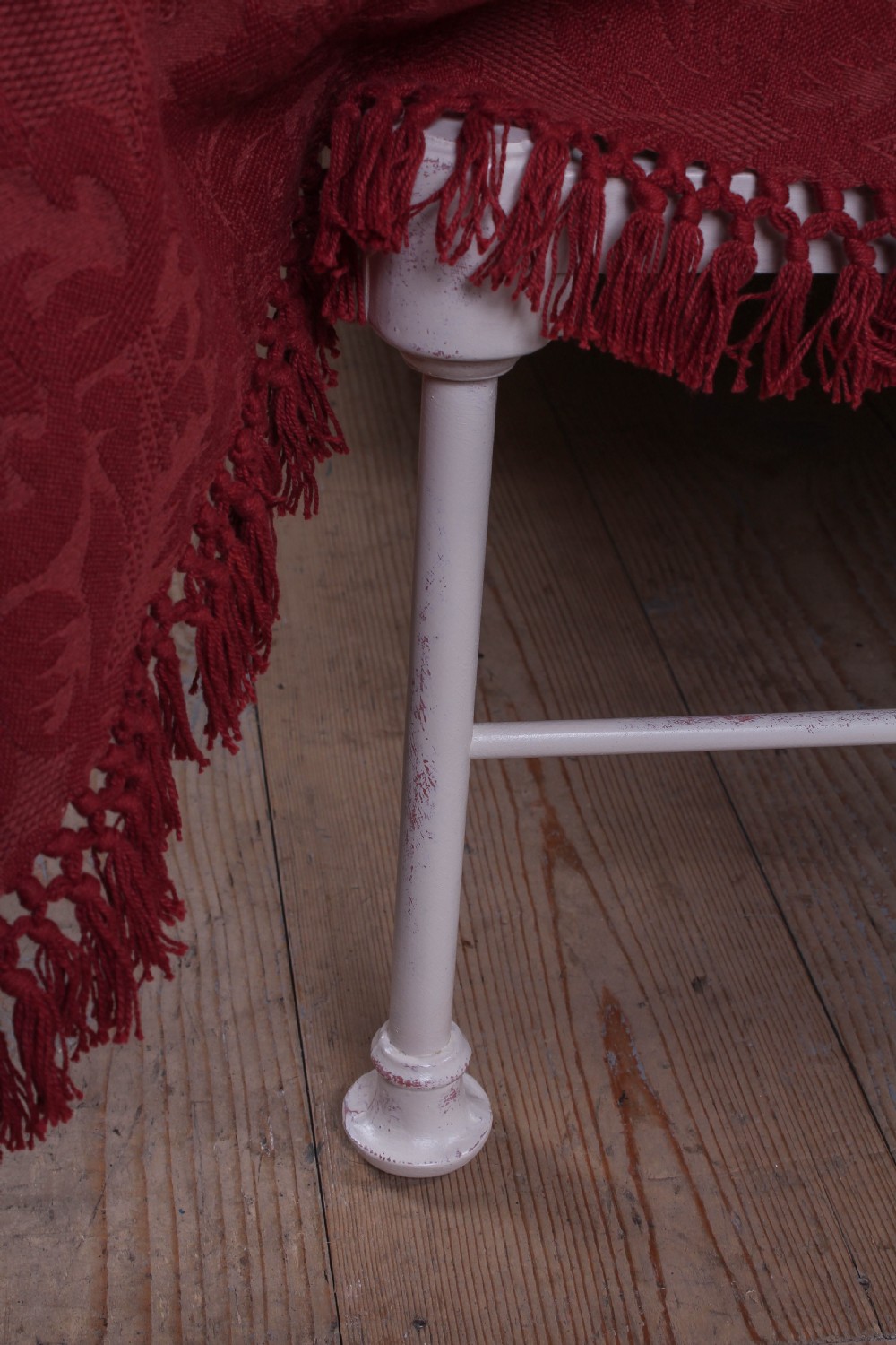 An off-white painted forged iron double bed frame featuring an arched headboard decorated with scrollwork and a low-profile foot end. View V