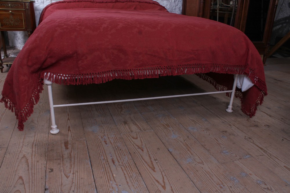 An off-white painted forged iron double bed frame featuring an arched headboard decorated with scrollwork and a low-profile foot end. View VII