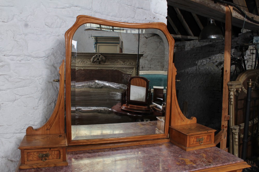 An Art Nouveau wooden bedroom suite featuring a curved double bedstead, matching dressing table with mirror, nightstand, and leather-upholstered side chairs. View XIII