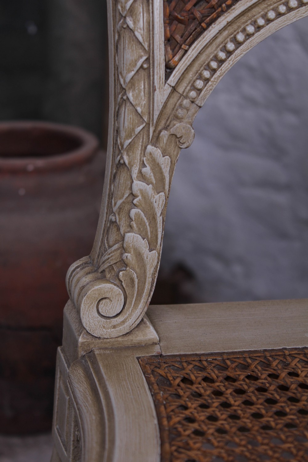 A French Louis XVI style super king bedstead featuring woven rattan cane panels, carved floral swags, and matching caned side chairs in a painted distressed finish. View XIII