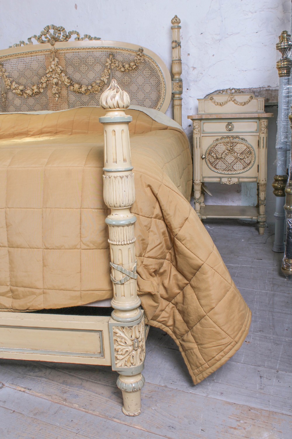 A cream and green painted super king size bedroom set featuring a detailed caned headboard, carved garlands, two matching bedside tables, and a chest of drawers with an oval mirror. View III