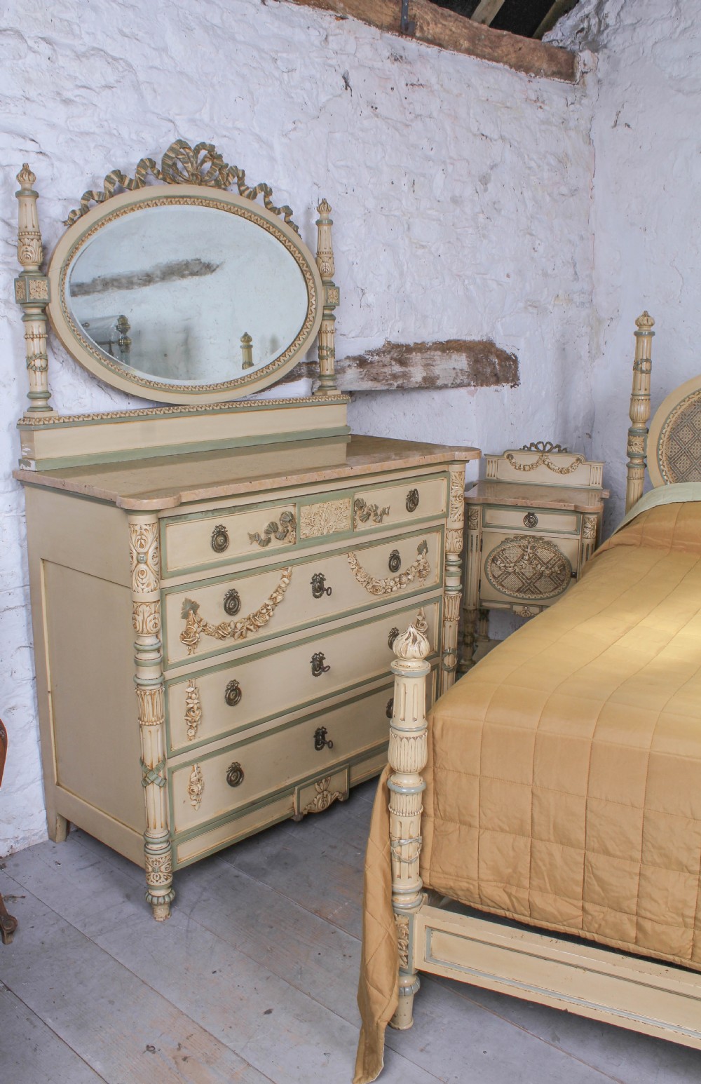 A cream and green painted super king size bedroom set featuring a detailed caned headboard, carved garlands, two matching bedside tables, and a chest of drawers with an oval mirror. View IV