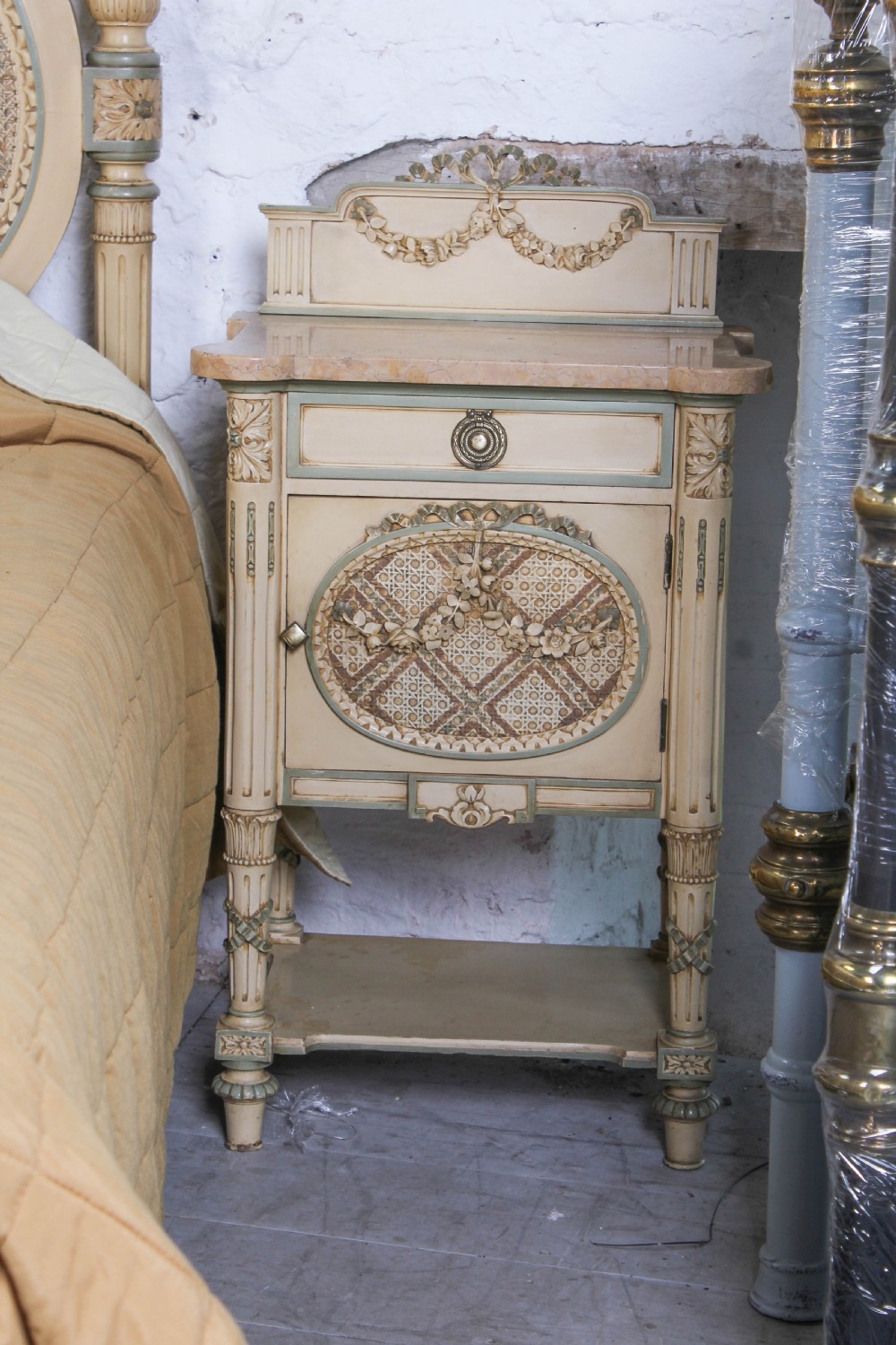 A cream and green painted super king size bedroom set featuring a detailed caned headboard, carved garlands, two matching bedside tables, and a chest of drawers with an oval mirror. View VIII