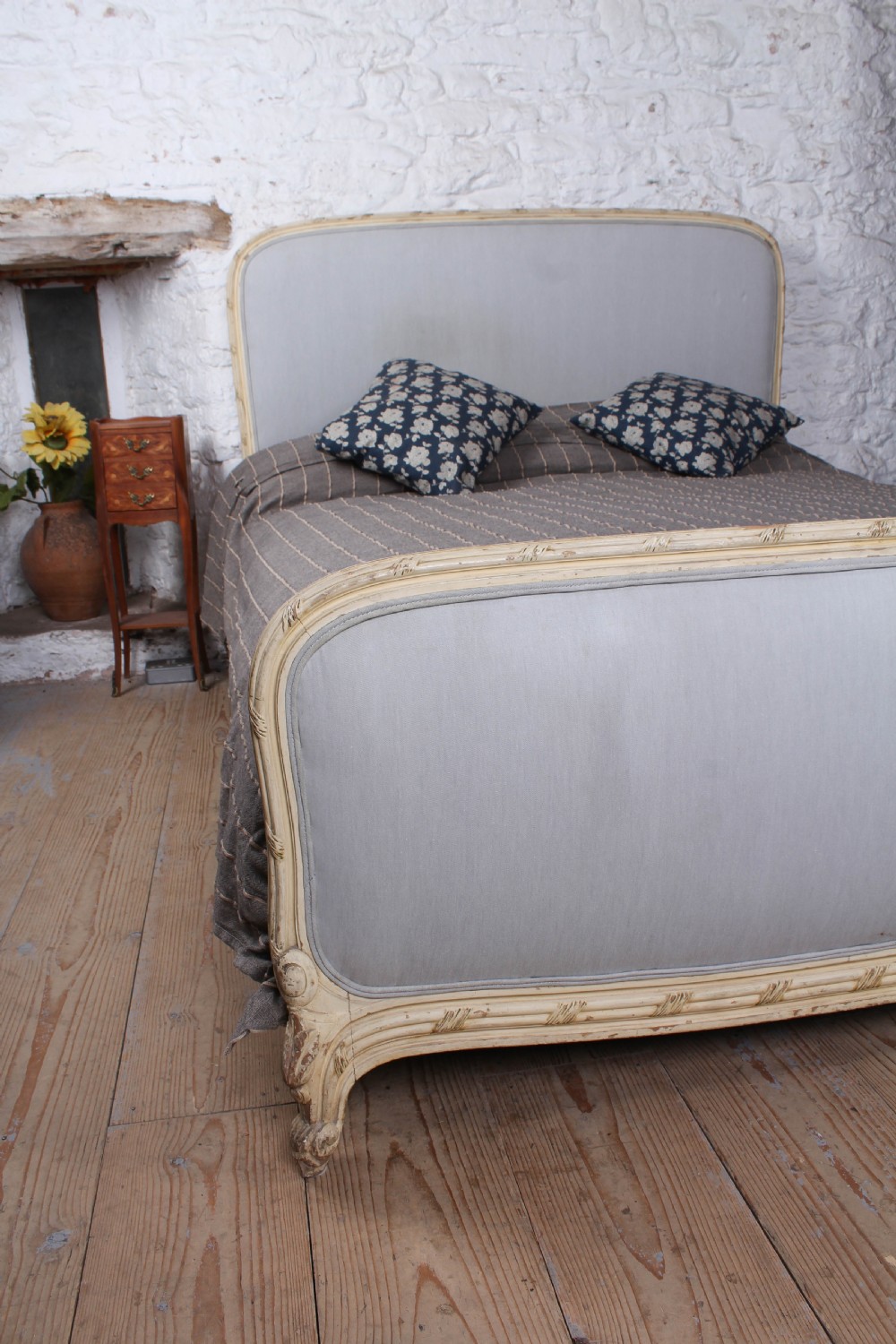 An antique French king-size bed featuring a cream painted carved wooden frame and light grey upholstered panels on the headboard and footboard. View IV