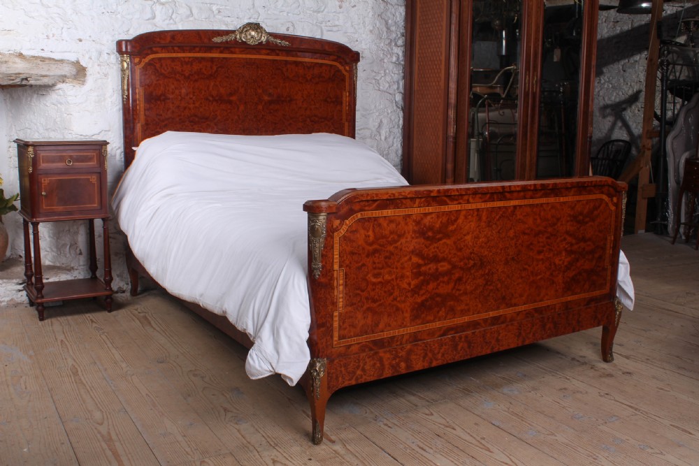 A French style kingsize bed frame in warm brown burr mahogany with fruitwood inlay borders and gilt metal corner mounts.