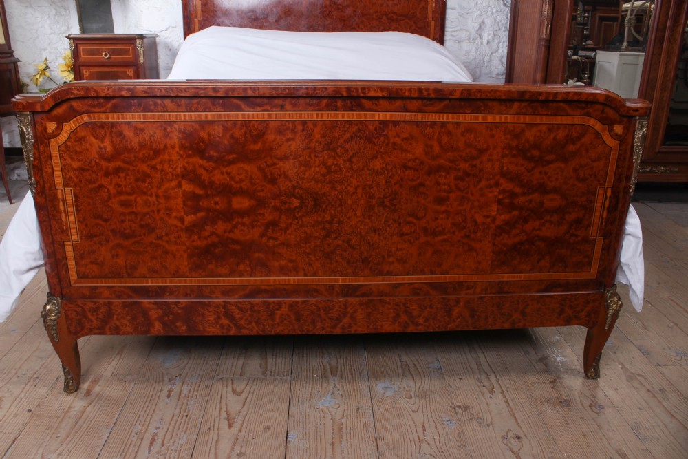 A French style kingsize bed frame in warm brown burr mahogany with fruitwood inlay borders and gilt metal corner mounts. View II