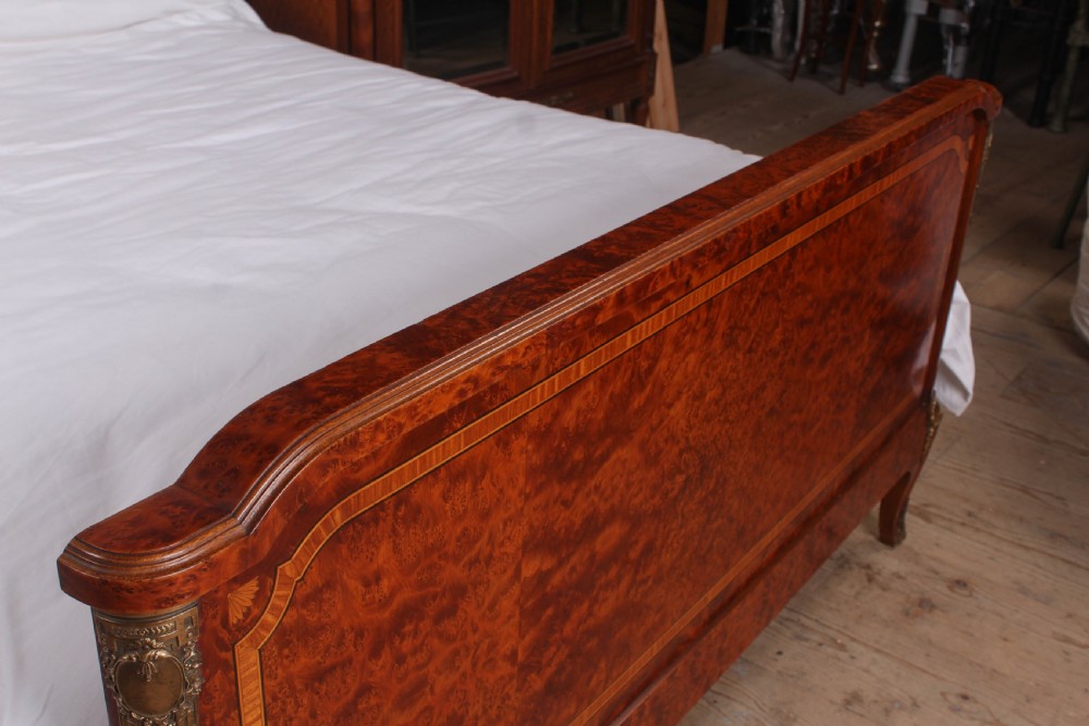 A French style kingsize bed frame in warm brown burr mahogany with fruitwood inlay borders and gilt metal corner mounts. View V