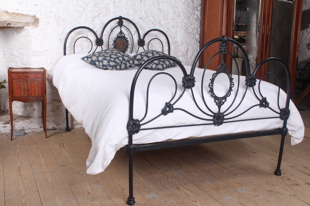 A Victorian black cast and wrought iron double bed frame featuring a three-hoop headboard and footboard with central decorative medallions.