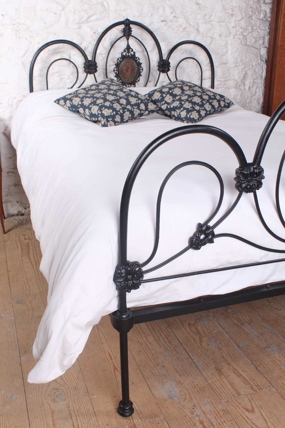A Victorian black cast and wrought iron double bed frame featuring a three-hoop headboard and footboard with central decorative medallions. View V