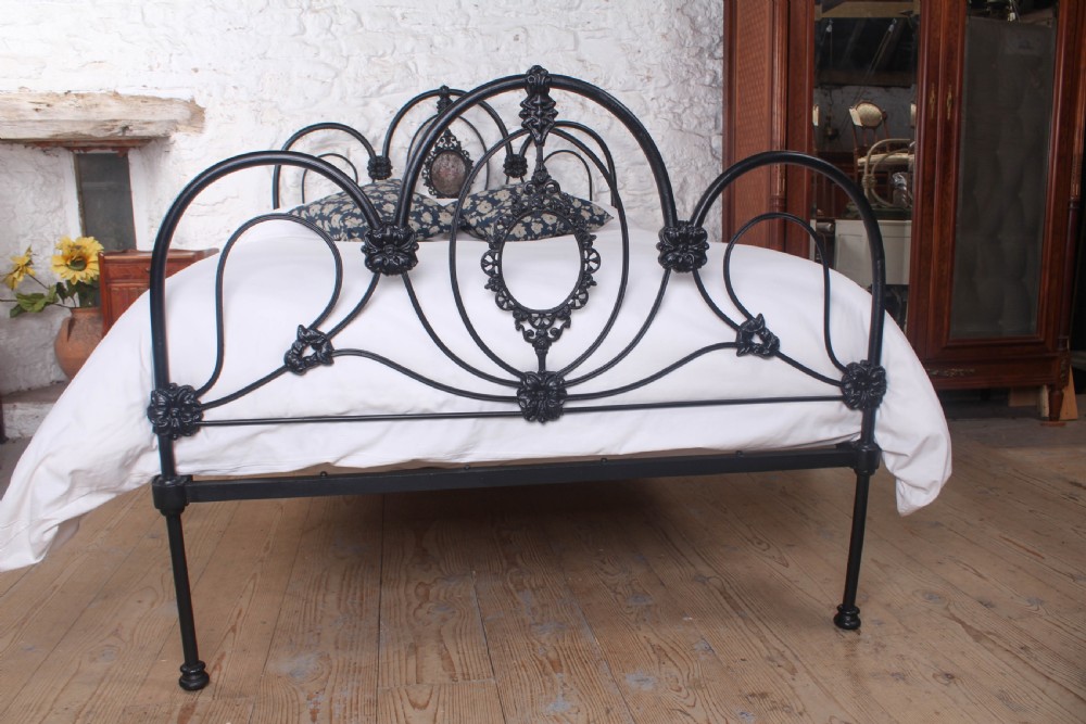 A Victorian black cast and wrought iron double bed frame featuring a three-hoop headboard and footboard with central decorative medallions. View VI