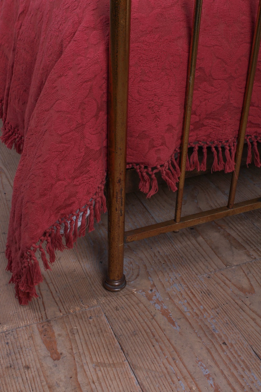 An antique single brass bedstead featuring vertical tubular spindles and a matching headboard and footboard with brass finials. View IV