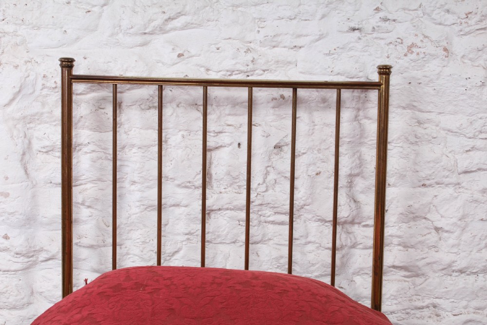 An antique single brass bedstead featuring vertical tubular spindles and a matching headboard and footboard with brass finials. View VII
