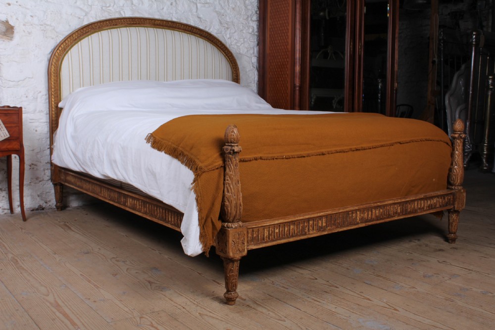 A Louis XVI style king size bed frame featuring a carved timber border, a striped upholstered arched headboard, and low carved corner posts. View VIII