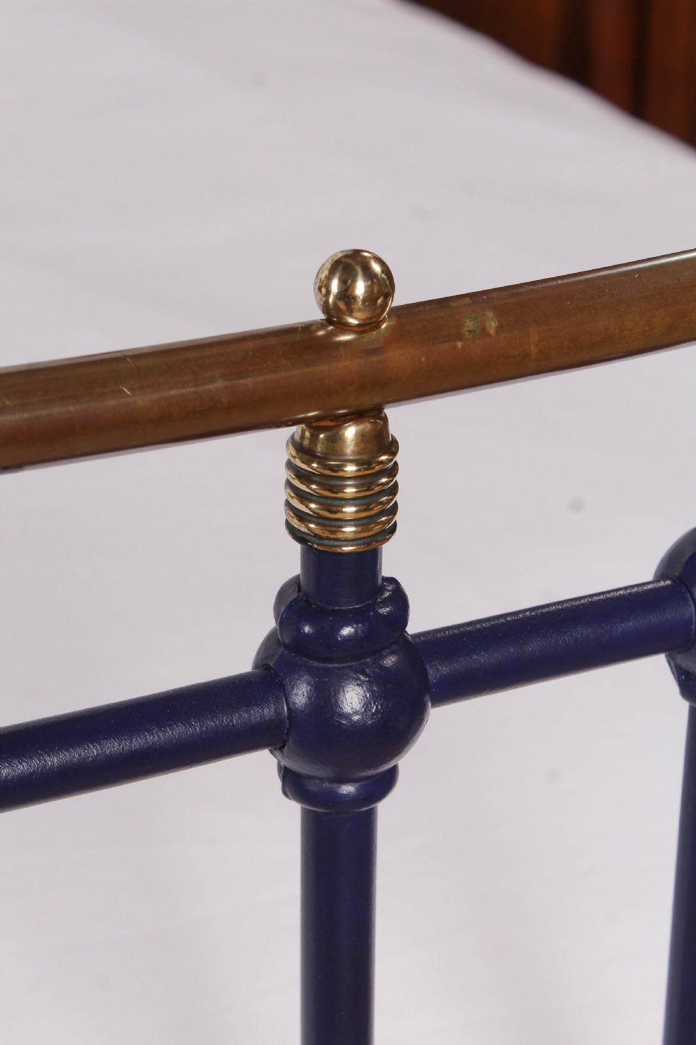 A Victorian metal double bedstead featuring a dark blue painted frame, vertical spindles, dipped brass top rails, and brass corner finials. View VIII