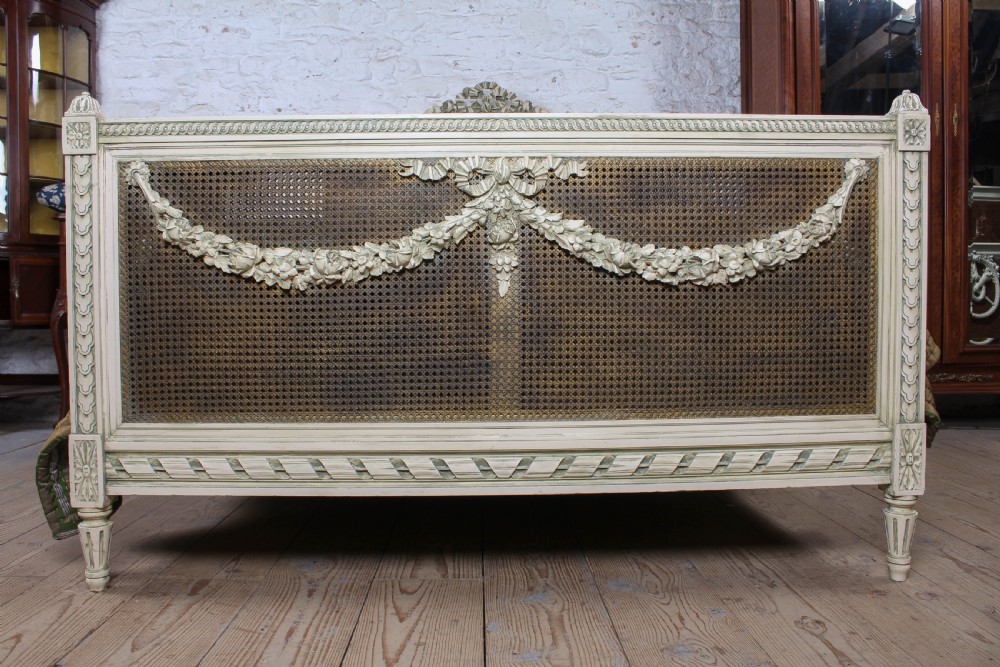 A painted Louis XVI style double bed frame featuring carved floral garlands, fluted corner posts, and woven cane panels in the headboard and footboard. View II