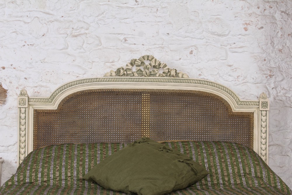 A painted Louis XVI style double bed frame featuring carved floral garlands, fluted corner posts, and woven cane panels in the headboard and footboard. View III