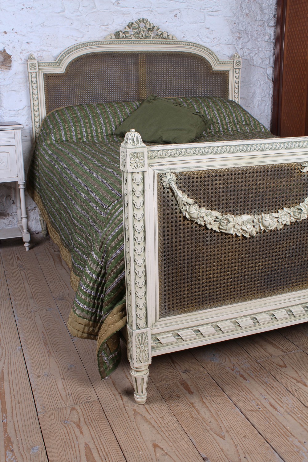 A painted Louis XVI style double bed frame featuring carved floral garlands, fluted corner posts, and woven cane panels in the headboard and footboard. View V
