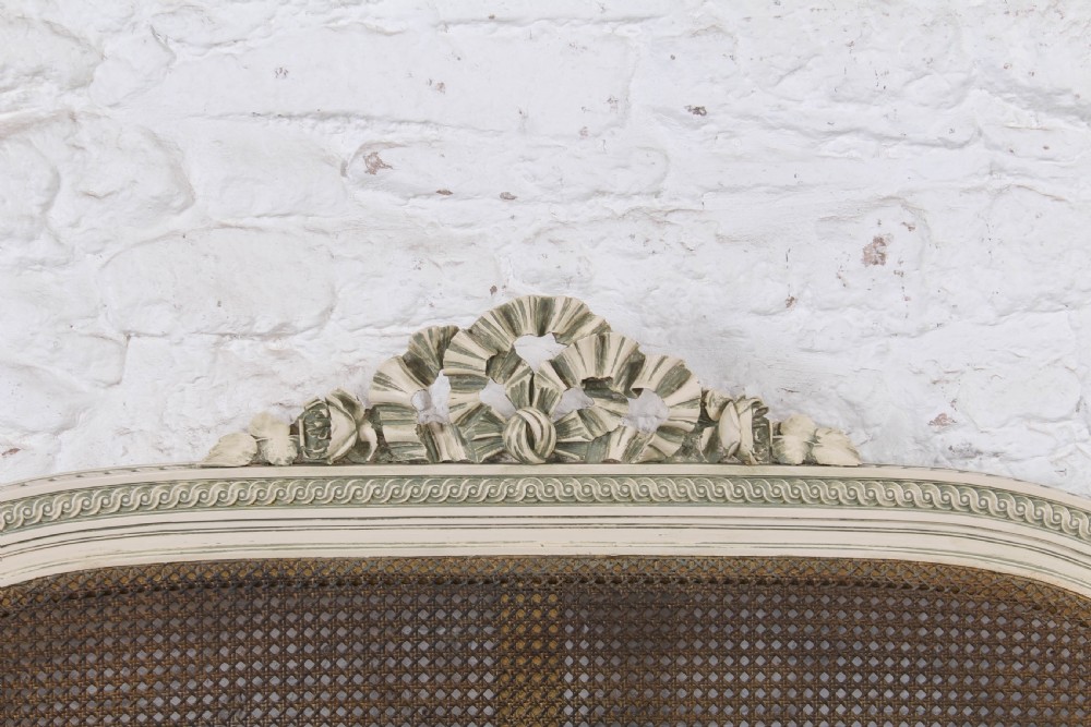 A painted Louis XVI style double bed frame featuring carved floral garlands, fluted corner posts, and woven cane panels in the headboard and footboard. View VII