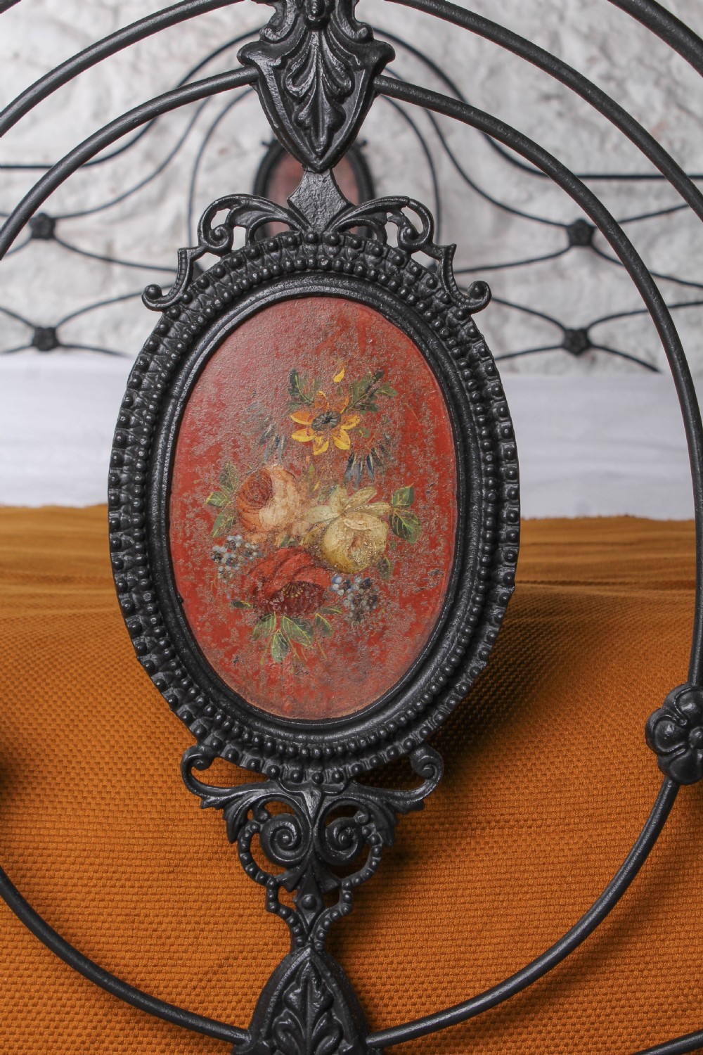 A Victorian black-painted cast iron bedstead featuring brass finials, arched lattice scrollwork, and oval floral enamel medallions on the headboard and footboard. View III