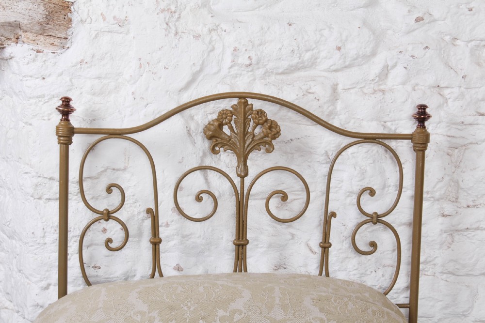 A pair of antique Portuguese small single metal beds featuring arched headboards with ornate metal scrollwork and central shell motifs. View V
