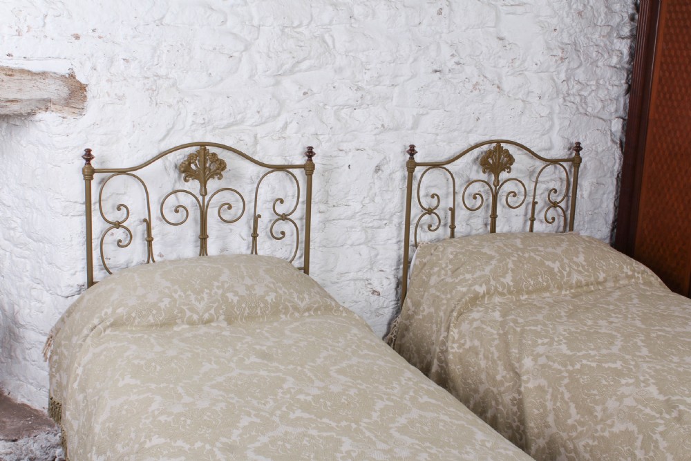 A pair of antique Portuguese small single metal beds featuring arched headboards with ornate metal scrollwork and central shell motifs. View VI