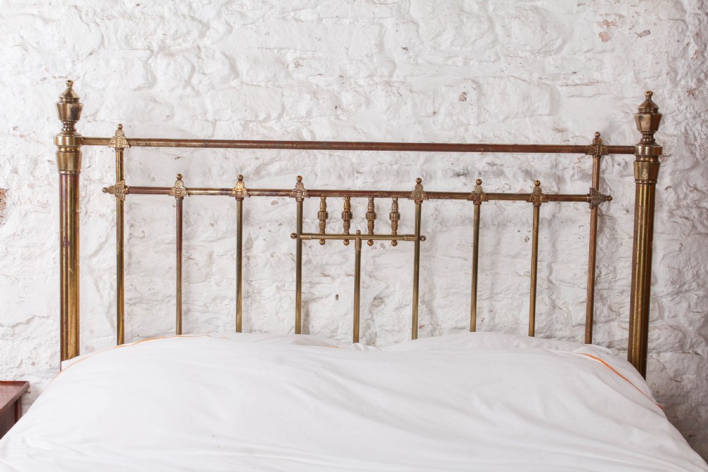 A Victorian king-size brass bed frame featuring detailed vertical spindles, geometric central motifs on the footboard, and turned corner posts with finials. View III
