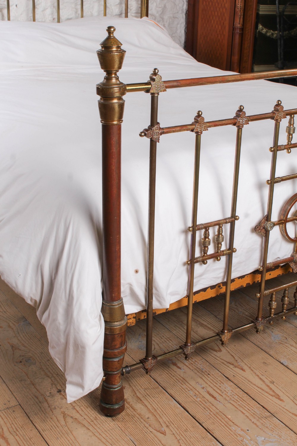 A Victorian king-size brass bed frame featuring detailed vertical spindles, geometric central motifs on the footboard, and turned corner posts with finials. View IV