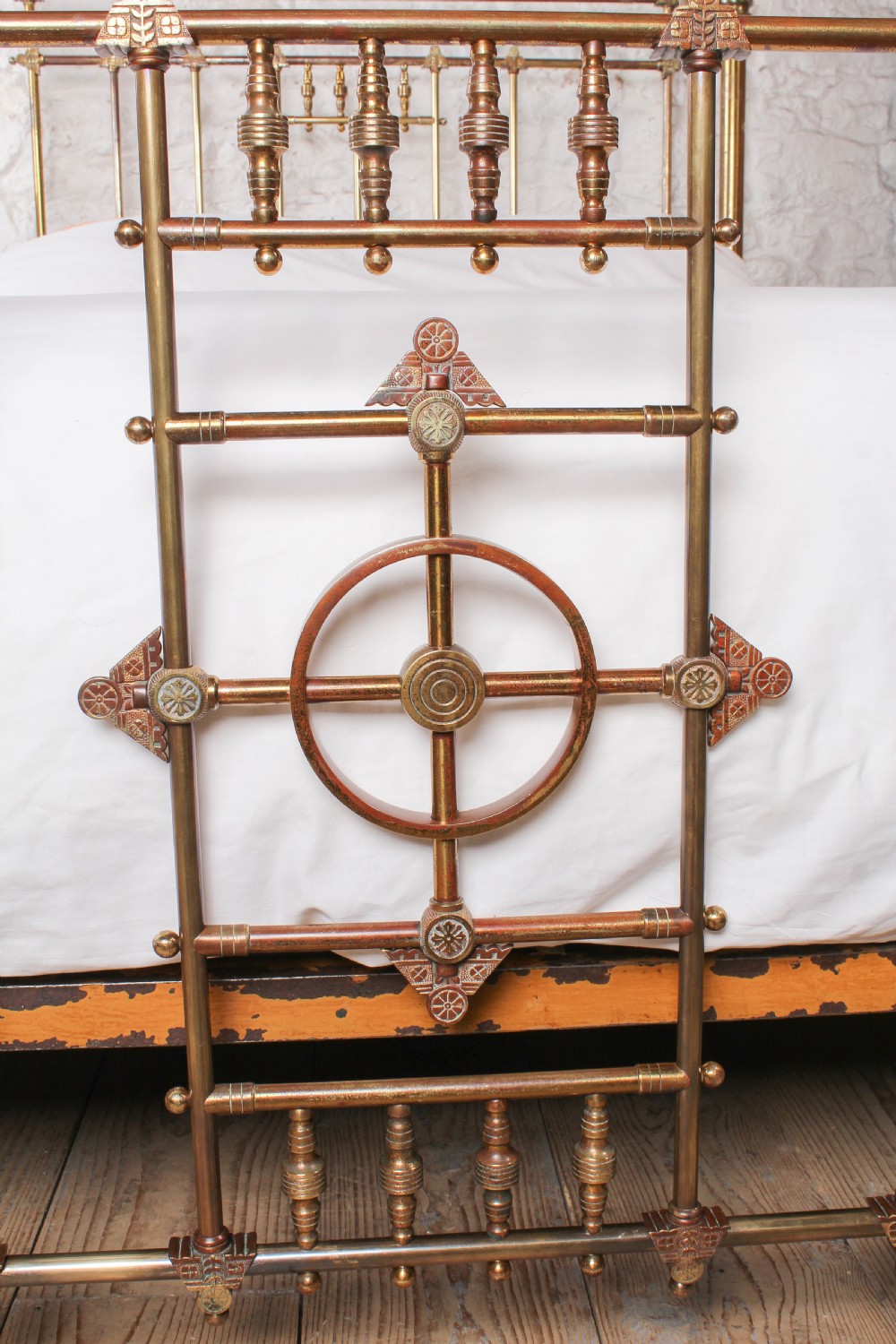 A Victorian king-size brass bed frame featuring detailed vertical spindles, geometric central motifs on the footboard, and turned corner posts with finials. View VIII
