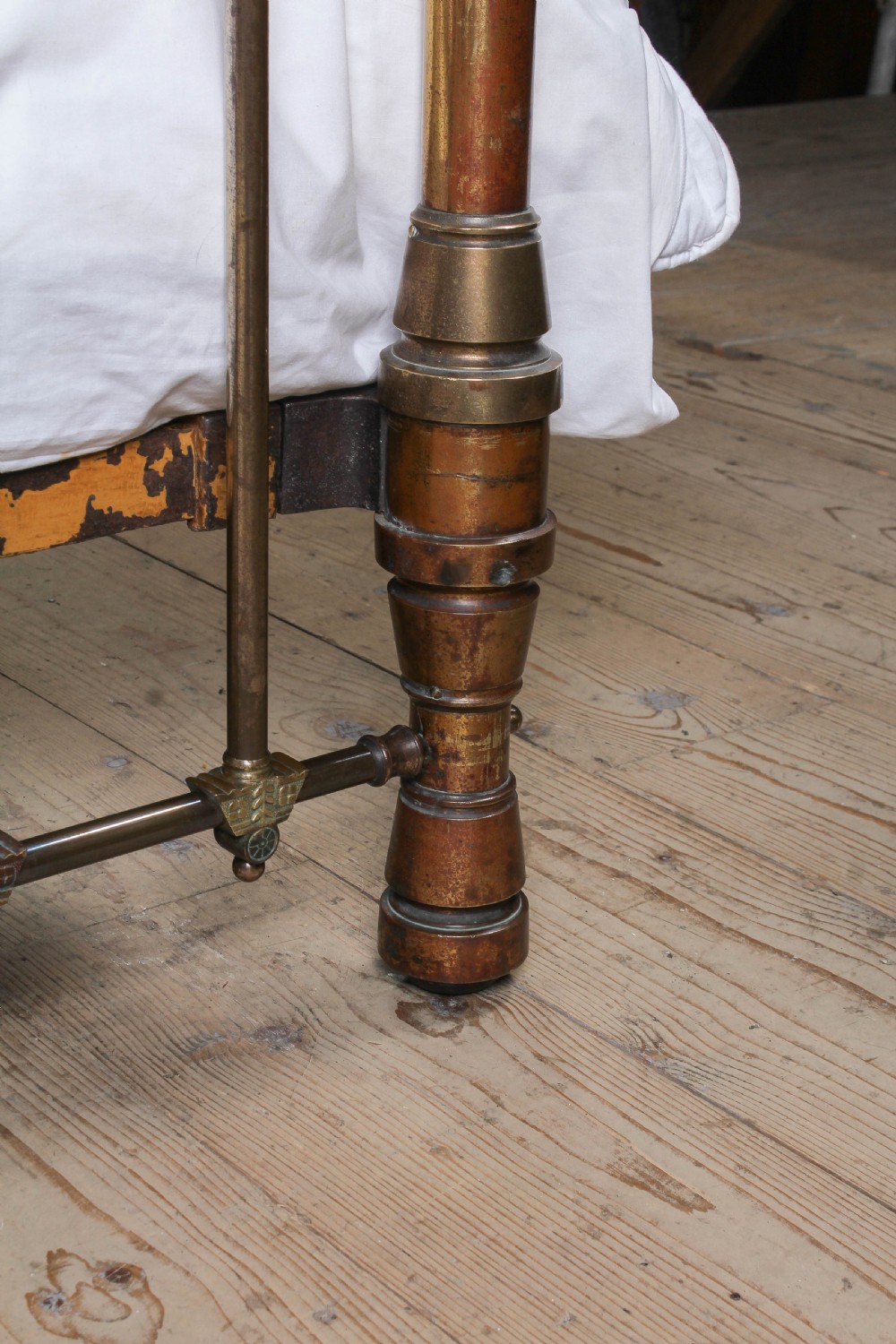 A Victorian king-size brass bed frame featuring detailed vertical spindles, geometric central motifs on the footboard, and turned corner posts with finials. View IX