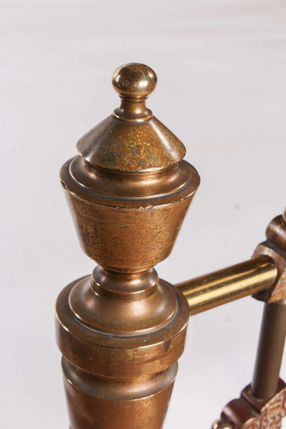 A Victorian king-size brass bed frame featuring detailed vertical spindles, geometric central motifs on the footboard, and turned corner posts with finials. View X