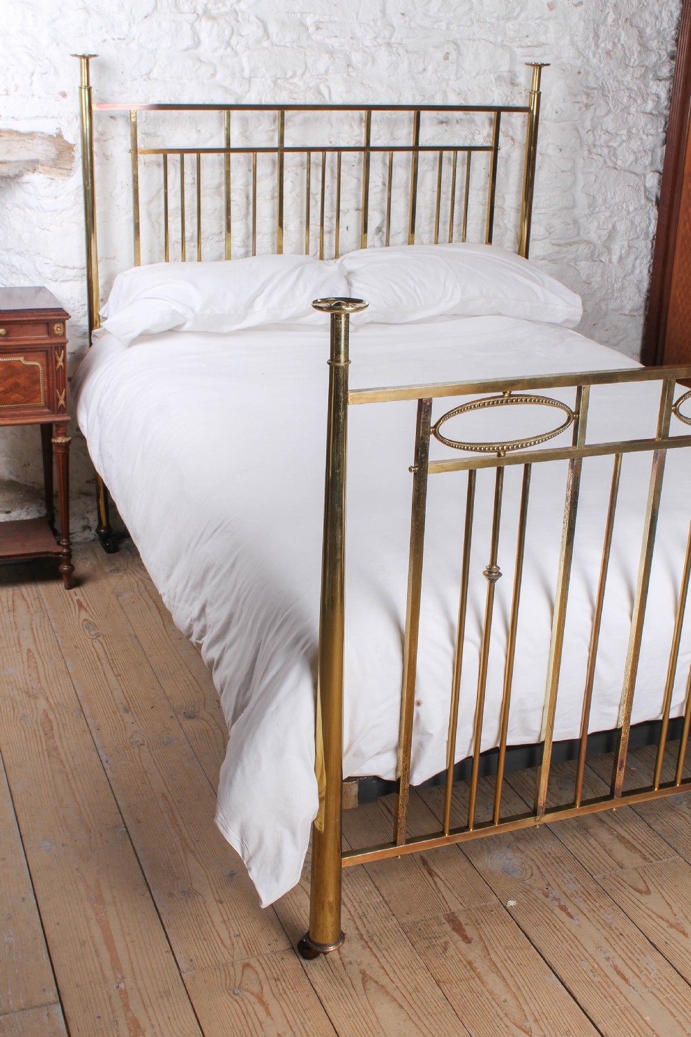 An antique brass king-size bed frame featuring vertical spindles, decorative oval motifs, and four tapered posts on castors. View III