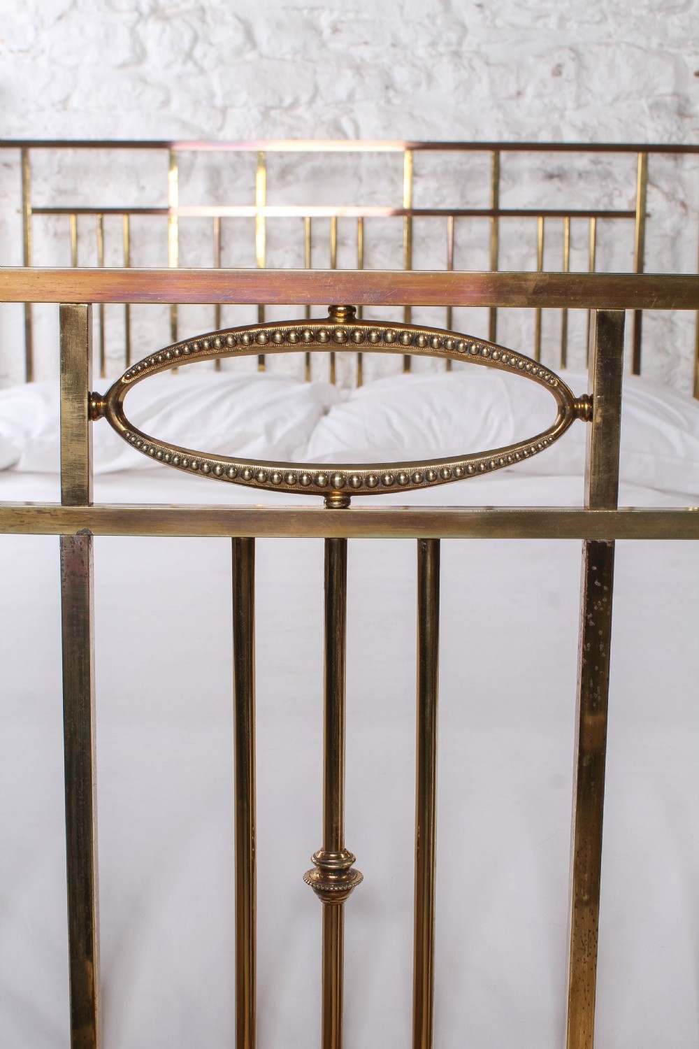 An antique brass king-size bed frame featuring vertical spindles, decorative oval motifs, and four tapered posts on castors. View IV