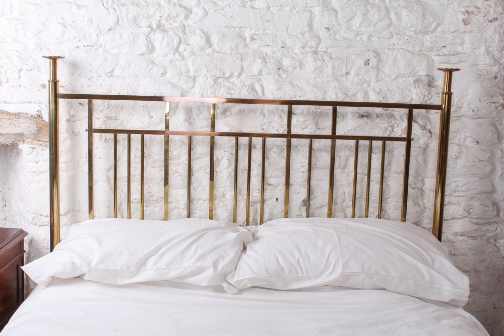 An antique brass king-size bed frame featuring vertical spindles, decorative oval motifs, and four tapered posts on castors. View VII