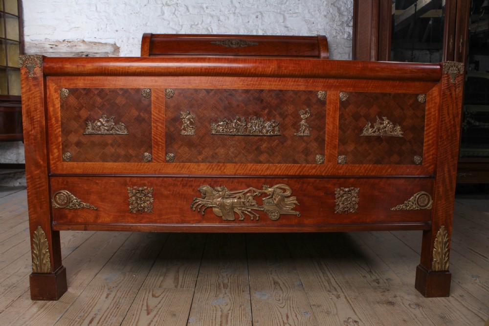 An Empire style mahogany double bedstead featuring rolled headboard profiles, parquetry panelwork, and decorative gilt-bronze mounts. View II