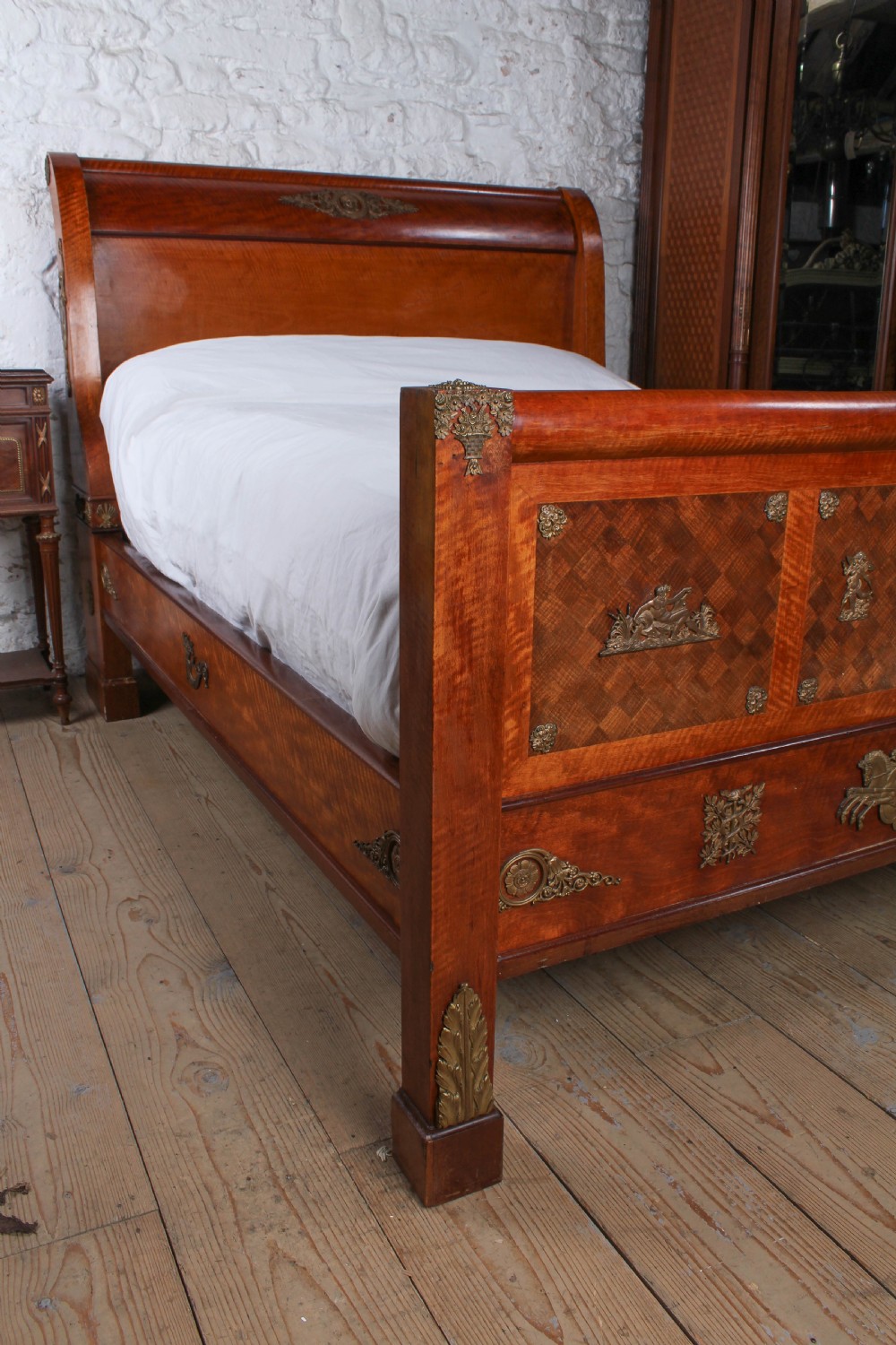 An Empire style mahogany double bedstead featuring rolled headboard profiles, parquetry panelwork, and decorative gilt-bronze mounts. View III