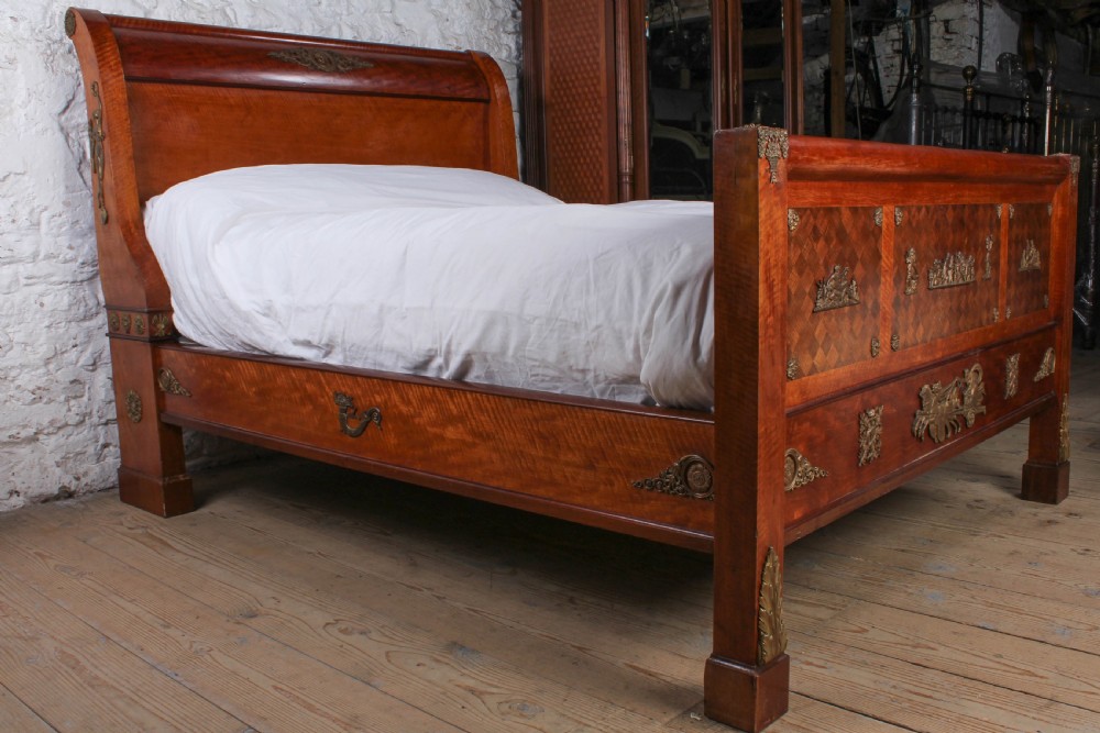 An Empire style mahogany double bedstead featuring rolled headboard profiles, parquetry panelwork, and decorative gilt-bronze mounts. View V