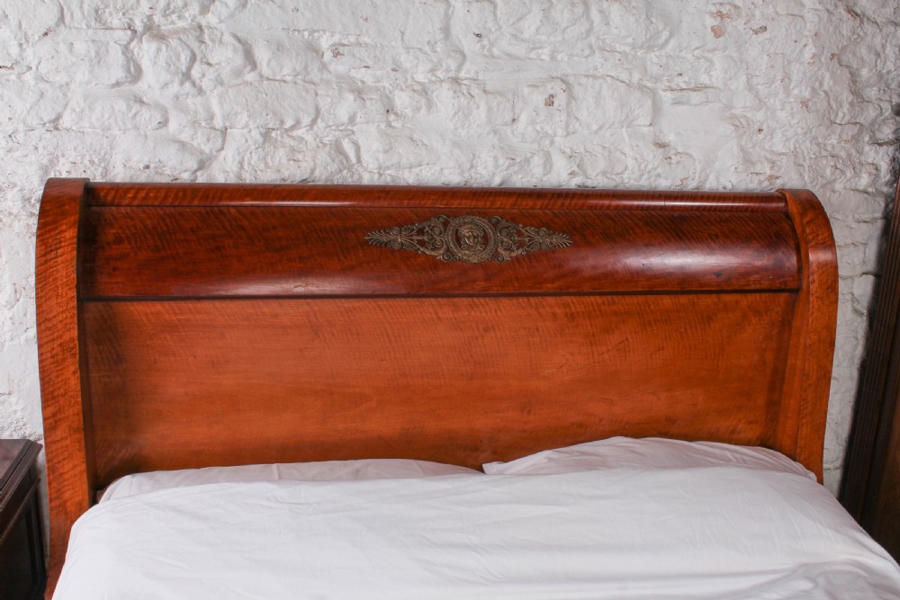 An Empire style mahogany double bedstead featuring rolled headboard profiles, parquetry panelwork, and decorative gilt-bronze mounts. View VI
