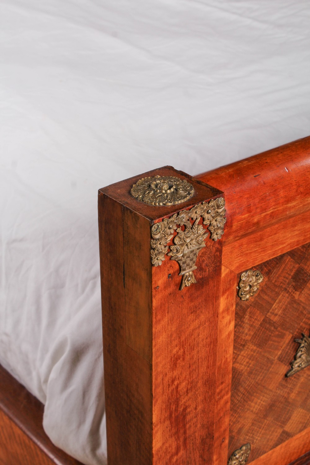 An Empire style mahogany double bedstead featuring rolled headboard profiles, parquetry panelwork, and decorative gilt-bronze mounts. View VII